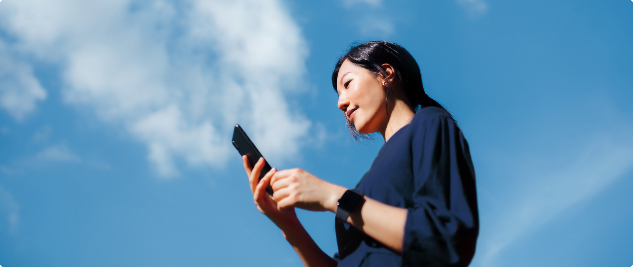 Mulher de azul com celular na mão Fotografia de mulher com camisa azul marinho, segurando o celular, usando smartwatch.