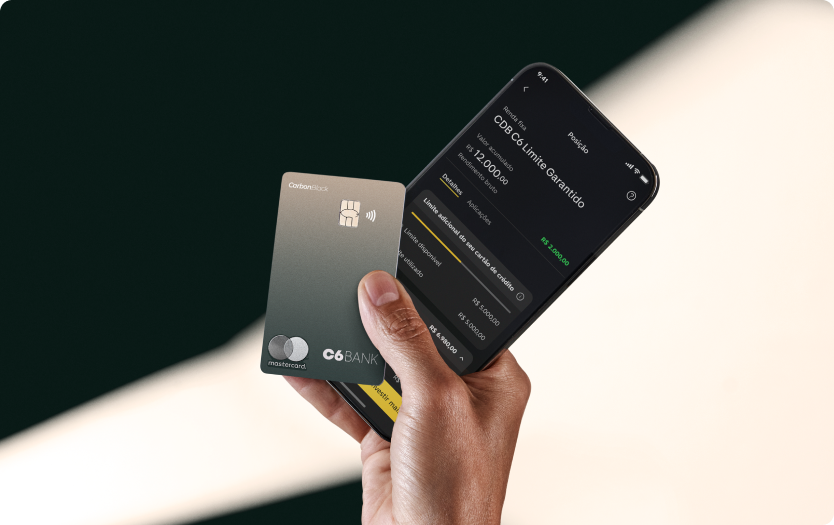 Mão segura um Cartão C6 Carbon Mastercard Black Boreal Forest e um celular com o app C6 Bank.