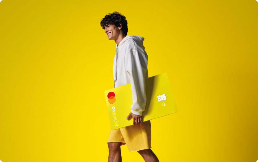 Menino sorri enquanto caminha segurando cartão C6 Yellow ampliado. Fundo e roupas seguem tom amarelo vibrante.
