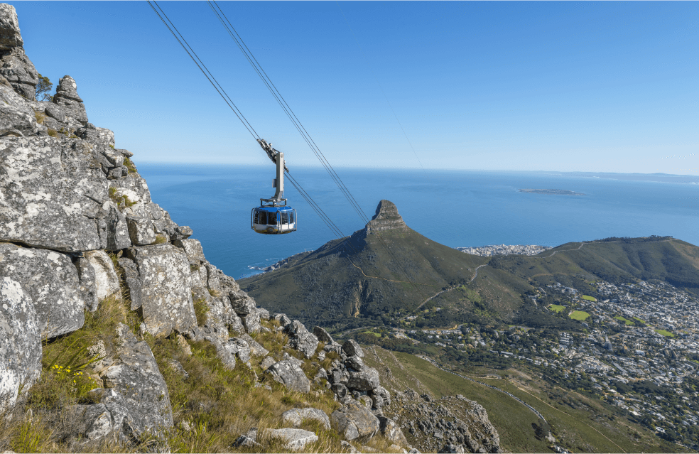 Bondinho passando por cima das montanhas da cidade e com fundo do mar azul