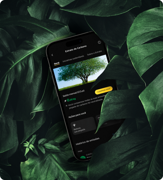 Celular com página "Extrato de Carbono" do app C6 Bank sobre neutralização de CO₂, em meio a folhas verdes.