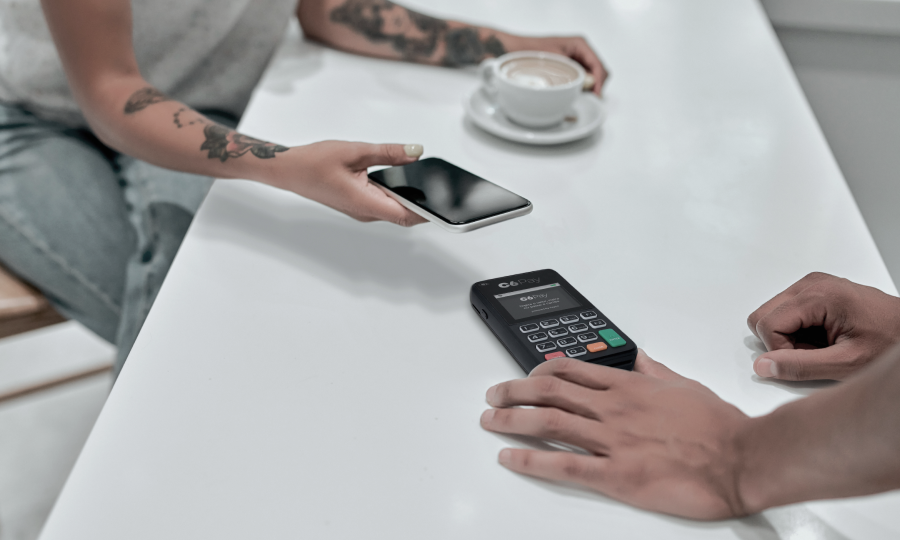 Foto de pessoa aproximando um celular em uma maquininha C6 Pay.
