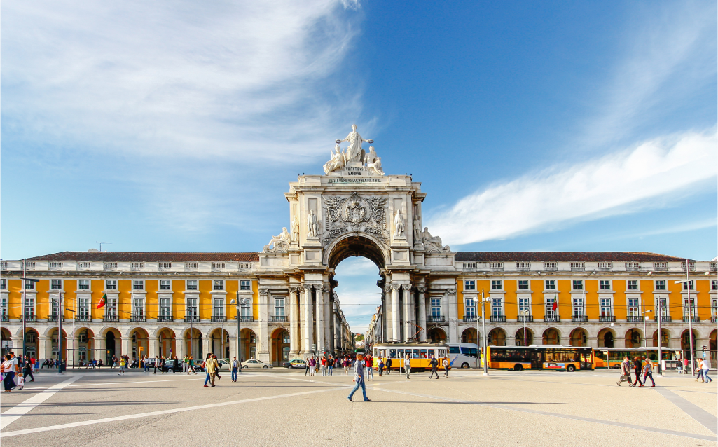 Imagem do Arco da Rua Augusta em Lisboa, um ícone arquitetônico da cidade com turistas ao redor e o céu azul ao fundo.