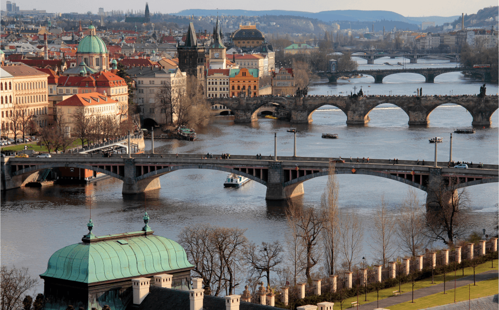 Vista dos vários pontes sobre o rio Moldava em Praga, com a cidade histórica ao fundo.