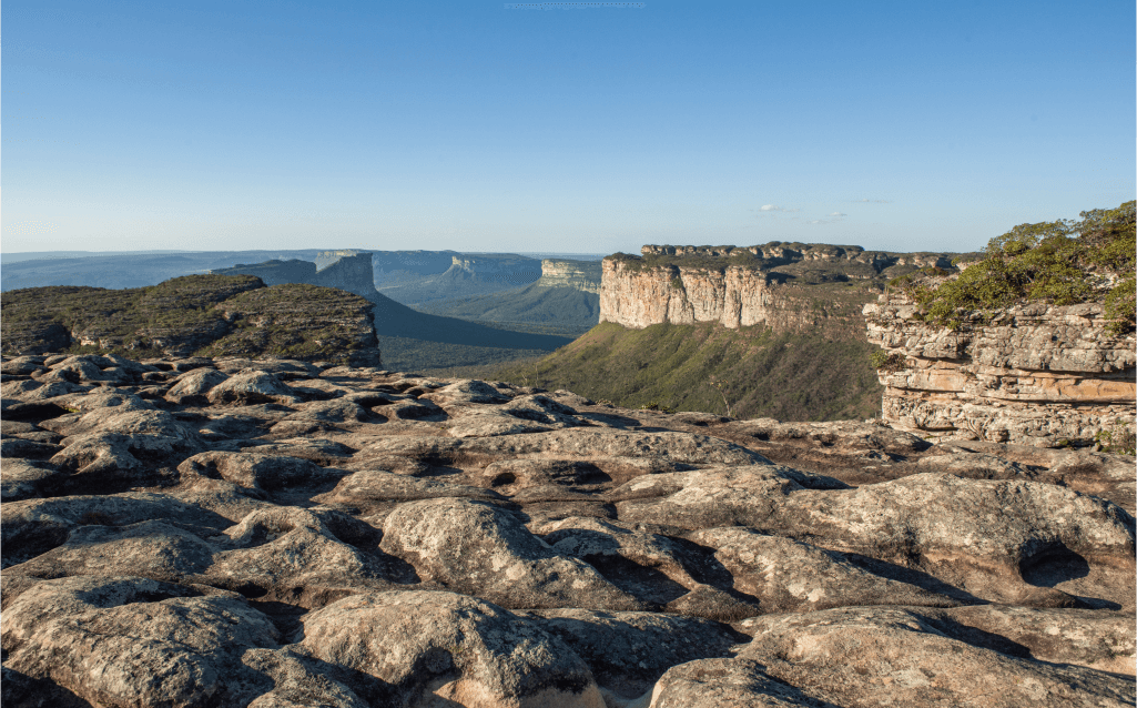 Vista do planalto rochoso e montanhas na Chapada Diamantina, Bahia, sob um céu azul.