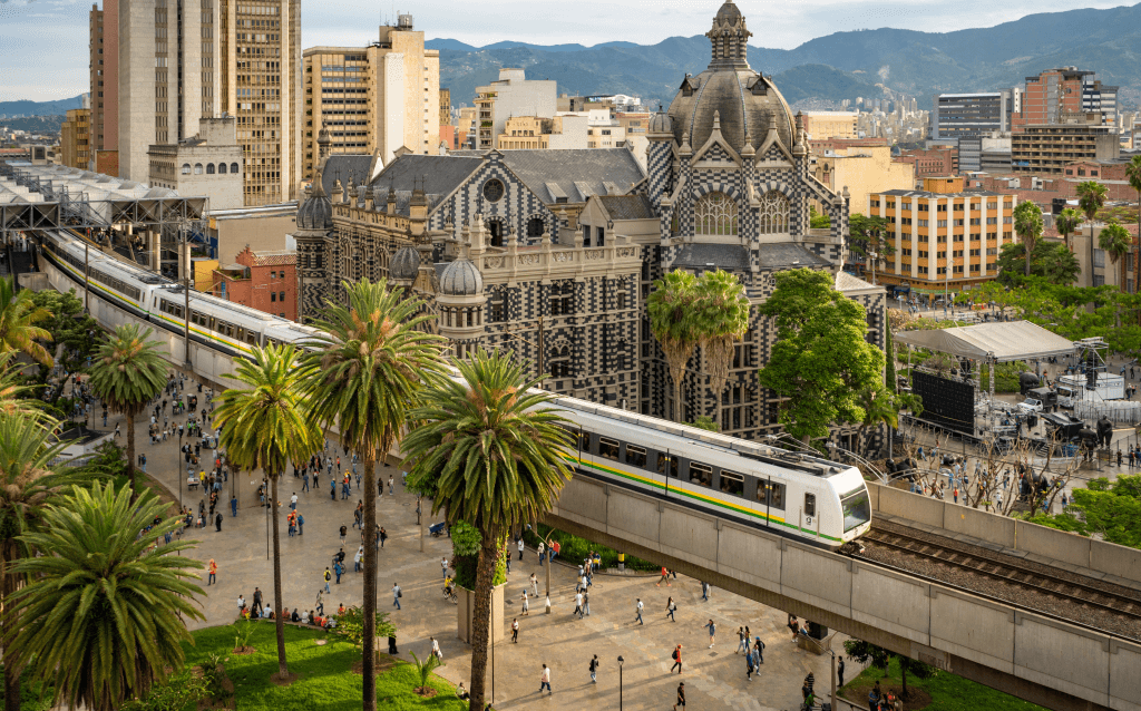 Vista do metrô elevado passando pela Praça Botero, em Medellín, com o Museu de Antioquia ao fundo.