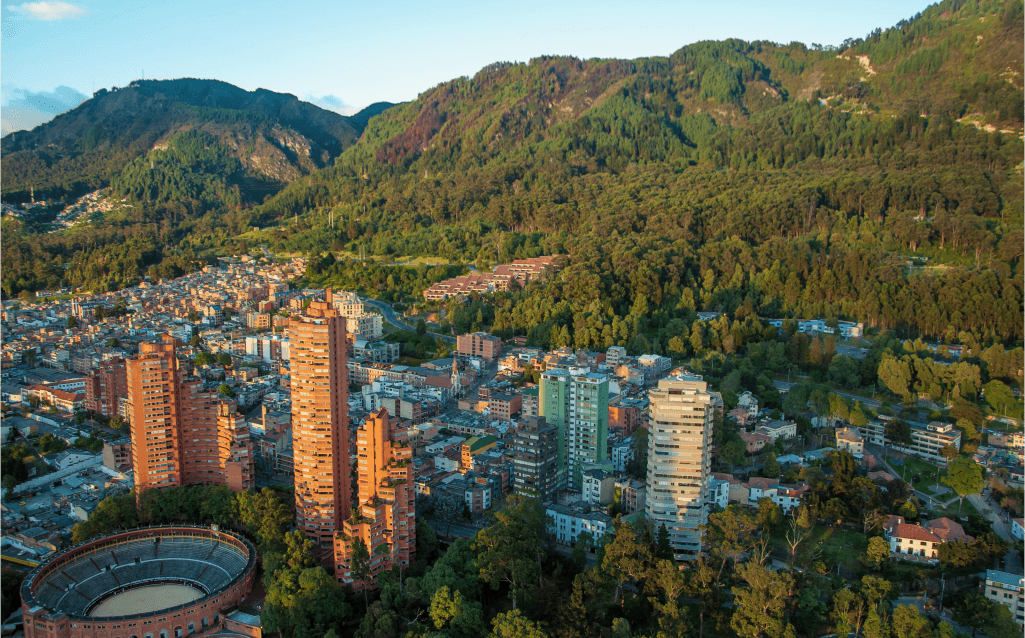 Vista aérea da cidade de Bogotá, Colômbia, cercada por montanhas e edifícios modernos.