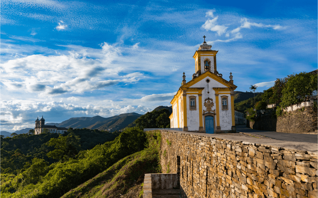 Igreja histórica de Ouro Preto, Minas Gerais, situada em uma colina com montanhas ao fundo.