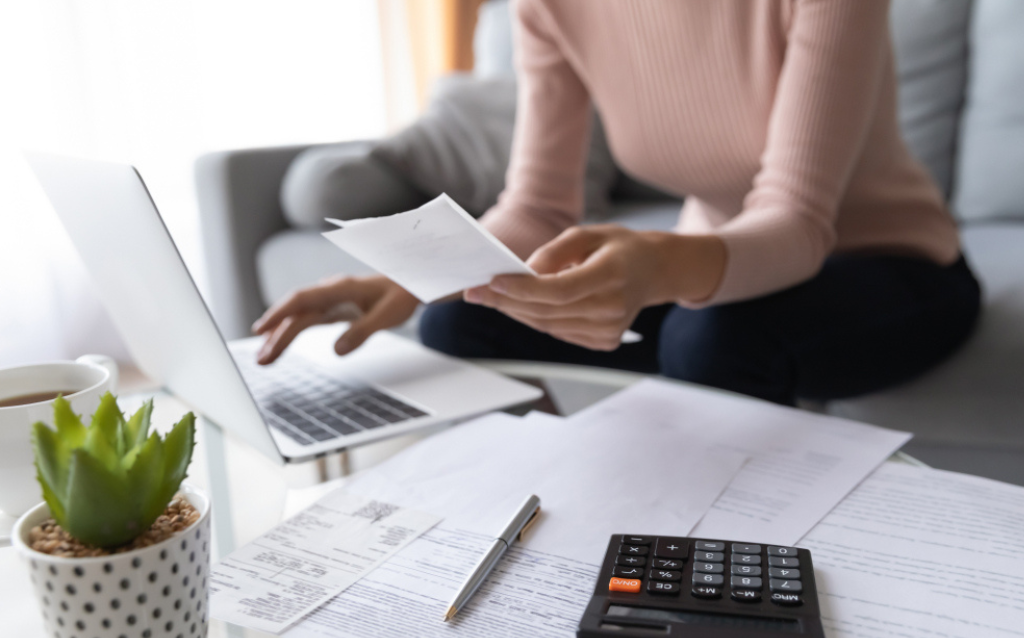 Pessoas segurando papel e pesquisando no computador sobre o balanço de fim de ano