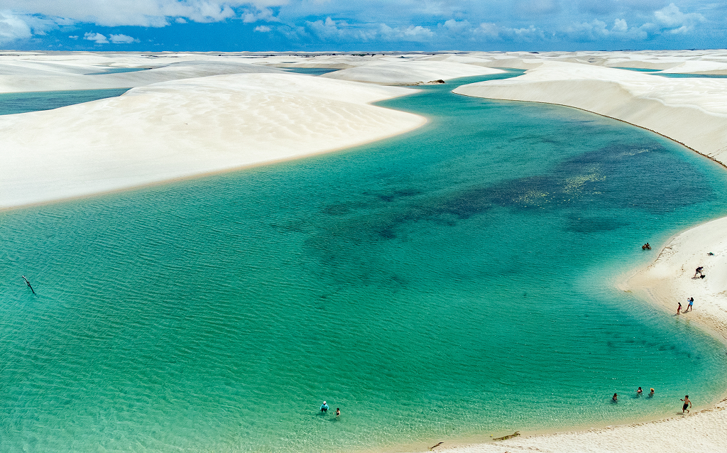 Vista aérea das lagoas azuladas e dunas de areia branca em Lençóis Maranhenses, um destino turístico popular no Brasil, ideal para atividades ao ar livre.