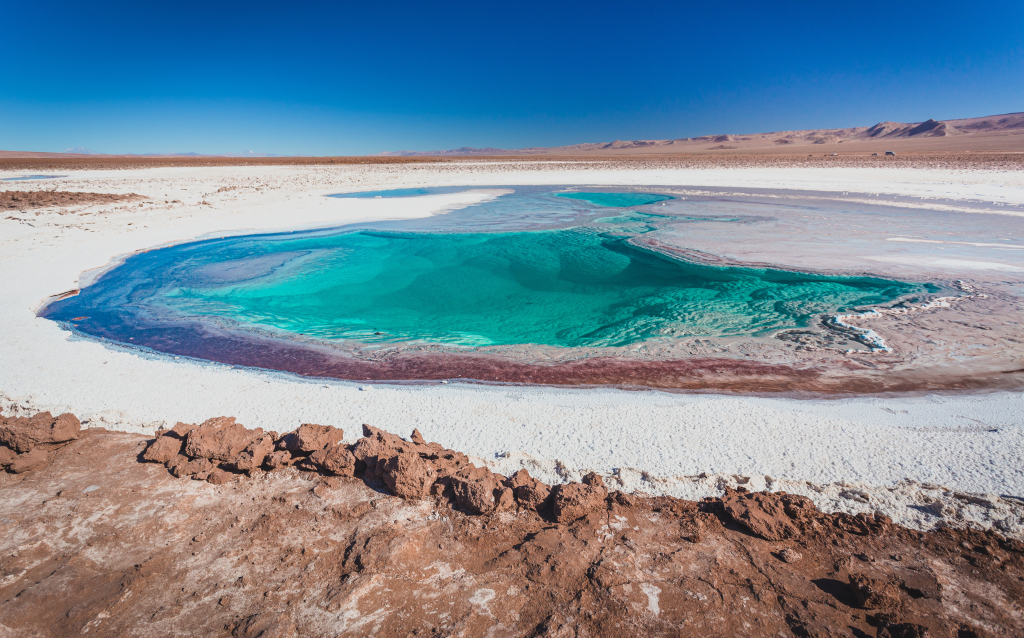 Imagem de uma lagoa cristalina em um deserto, destacando suas águas azul-turquesa e a paisagem ao redor, perfeita para turismo e exploração na natureza.