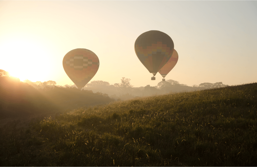 Diversos balões voando durante o pôr do sol.