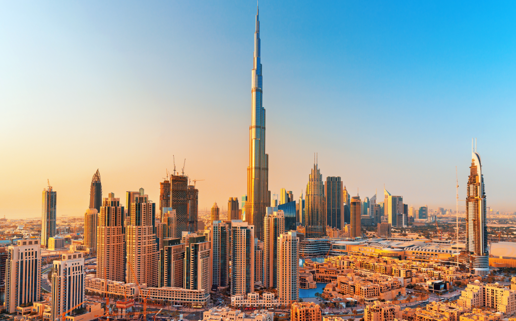 Vista panorâmica da cidade de Dubai com o imponente Burj Khalifa ao centro, rodeado por arranha-céus modernos durante o pôr do sol.