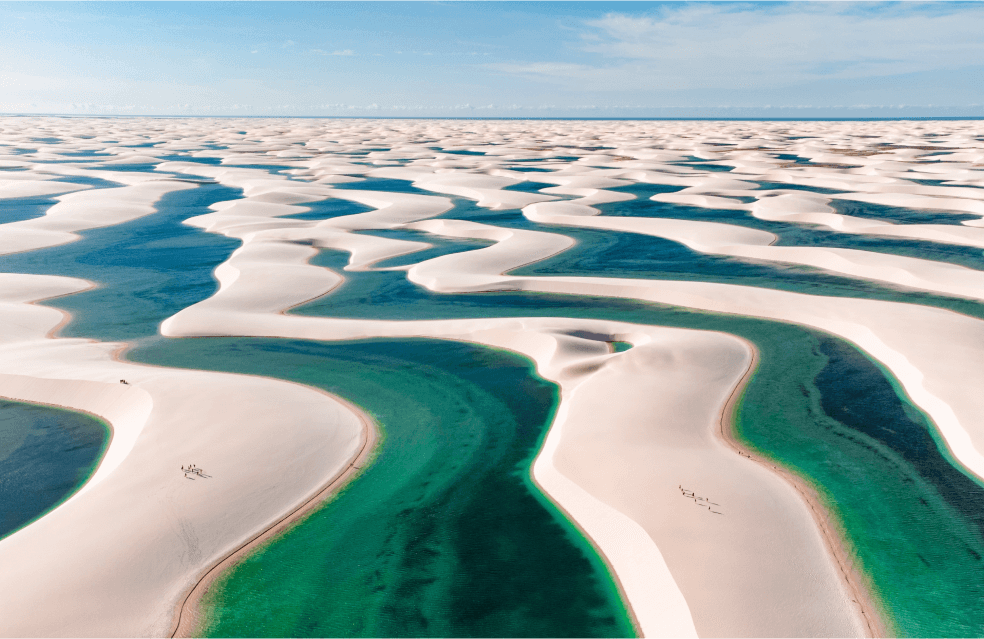 Dunas de areia intercaladas com lagos com água verde.