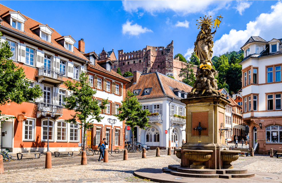 Foto de uma rua com construções tradicionais e uma praça com uma estátua no meio.