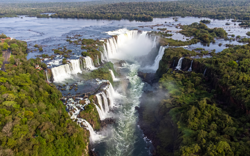 Vista aérea das Cataratas do Iguaçu, mostrando a imponente queda d'água cercada por vegetação exuberante e um cenário natural deslumbrante.