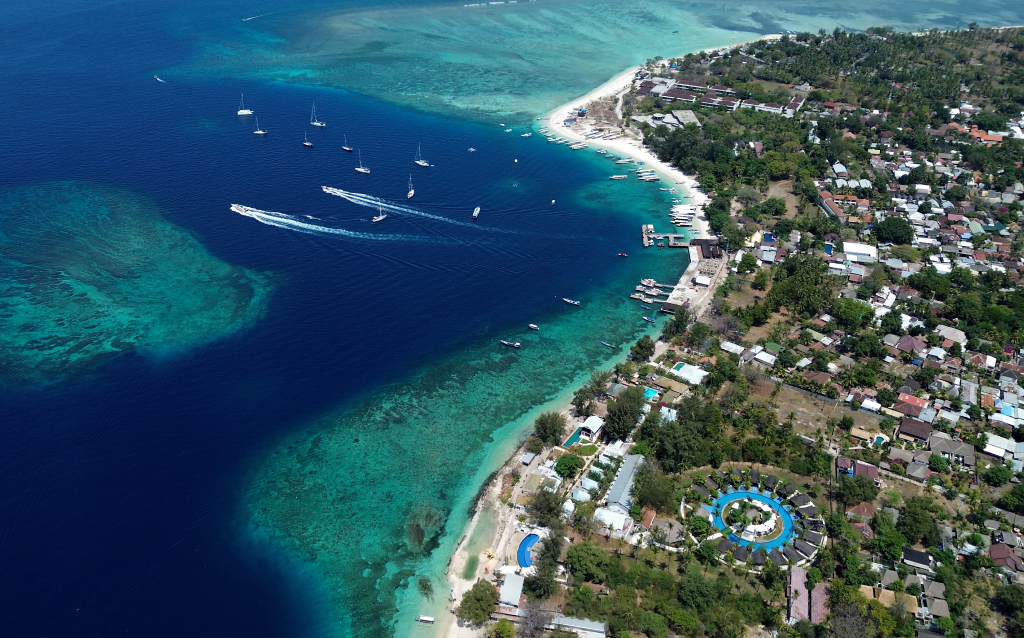   Vista aérea deslumbrante de uma costa tropical com águas azul-turquesa e barcos navegando. Ideal para quem busca tranquilidade e beleza natural.