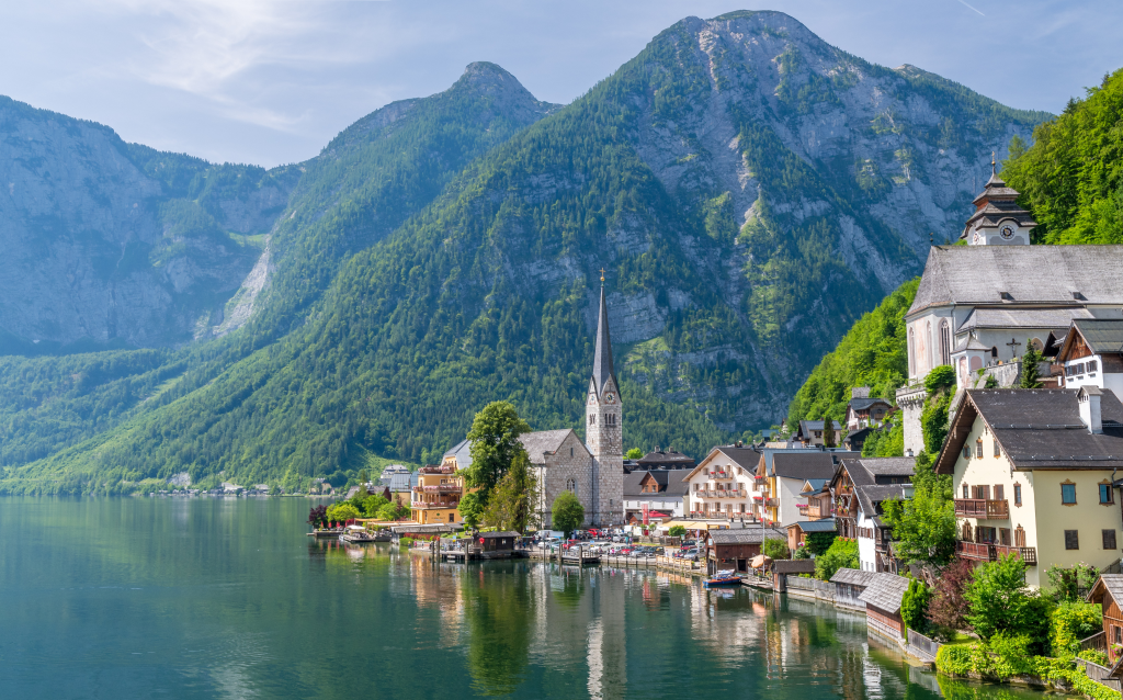 Vista panorâmica do lago e das montanhas em Hallstatt, na Áustria, destacando a arquitetura encantadora das casas e a igreja local.