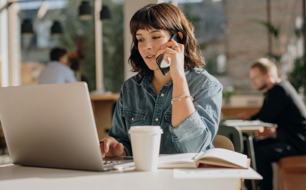 Mulher no telefone pesquisando no computador informações sobre o balanço de fim de ano