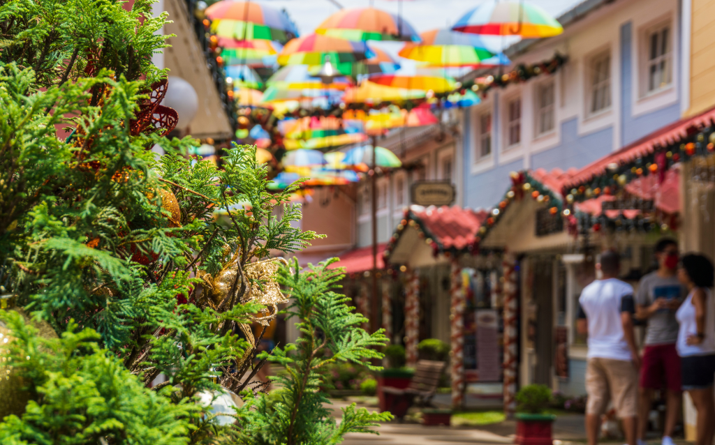 Rua decorada com guarda-chuvas coloridos e uma árvore de natal, criando um ambiente festivo e alegre. Ideal para passeios e fotografias.