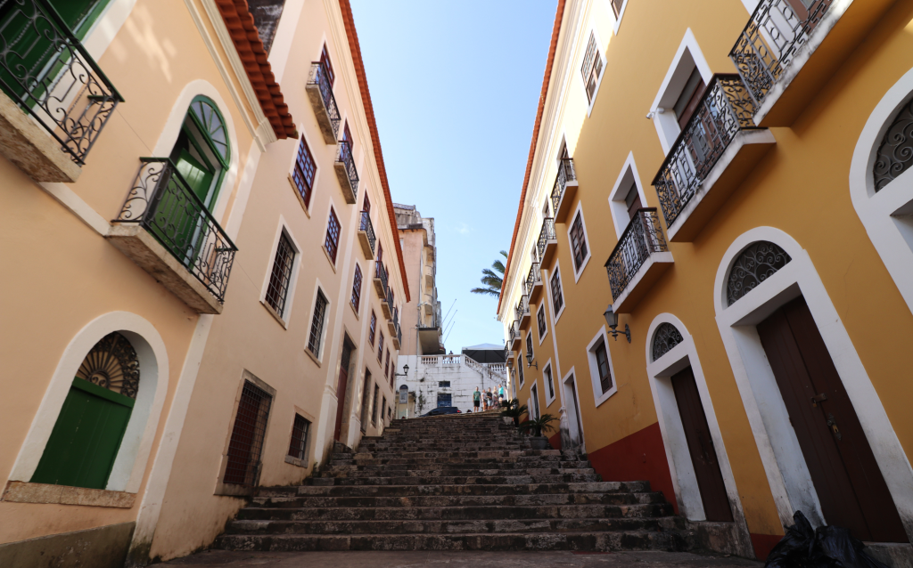 Vista de uma rua histórica com casas coloridas e escadas em um dia ensolarado, destacando a arquitetura típica brasileira.