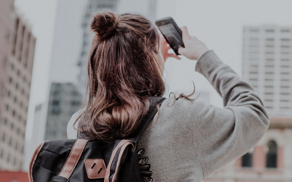 Mulher com cabelo preso e mochila nas costas segurando uma mochila e sendo o tipo de perfil de viajante cultural