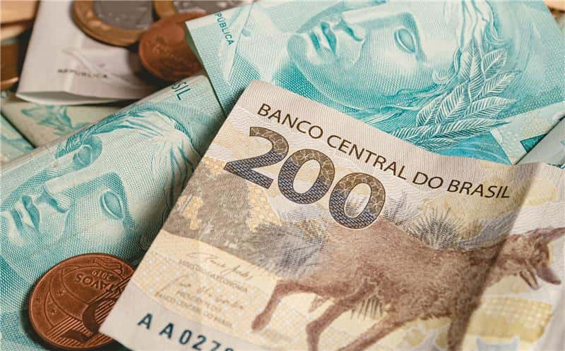 Cédulas e moedas brasileiras em destaque, incluindo a nota de 200 reais do Banco Central do Brasil, simbolizando a economia e finanças no país.