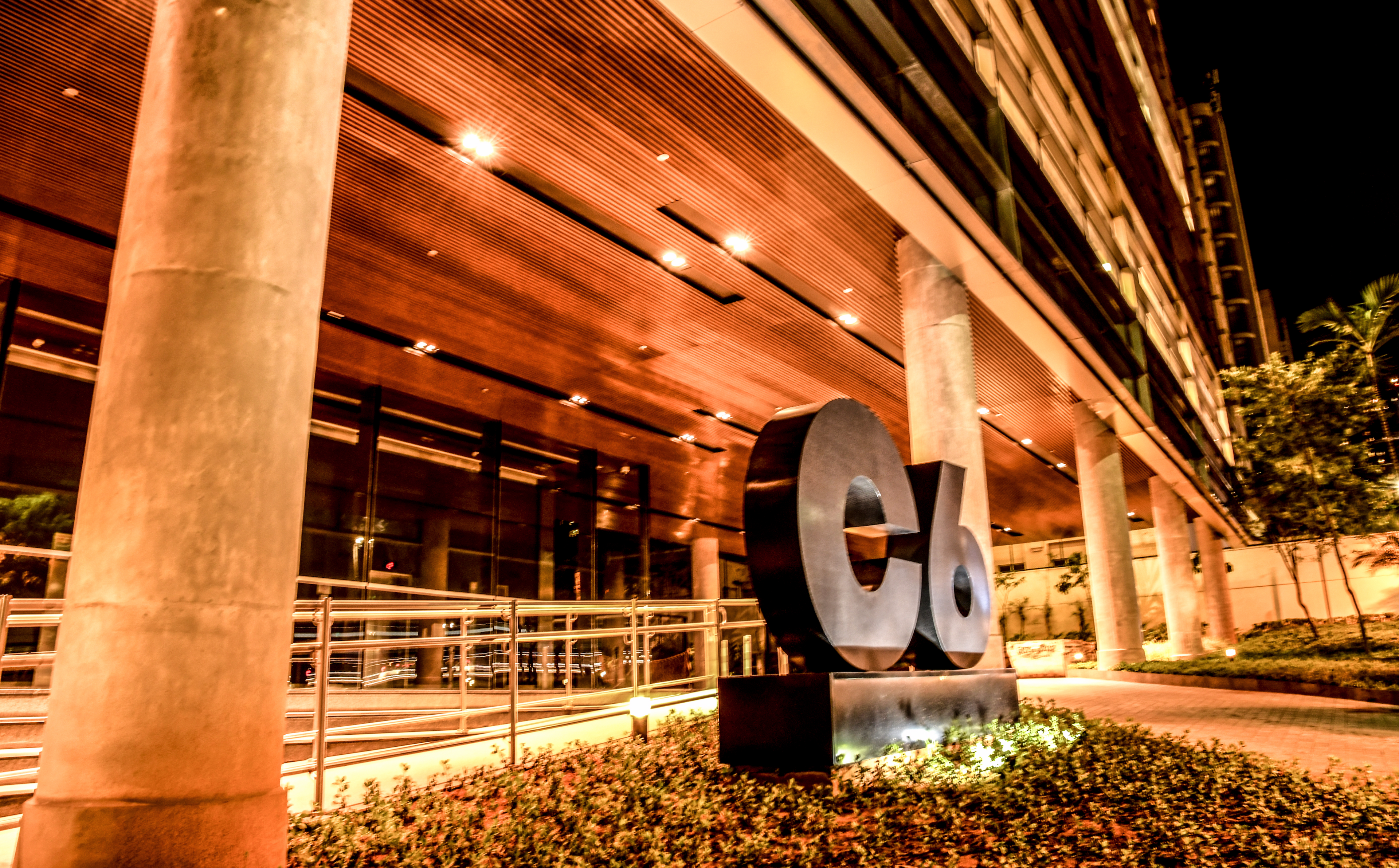 Fachada do prédio Carbon do C6 Bank com estátua do C6 iluminado durante a noite. como passar em um processo seletivo