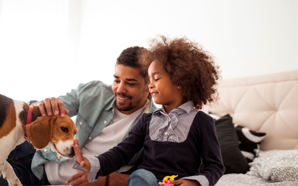 pai e filho negros brincam com cachorro beagle na sala de estar